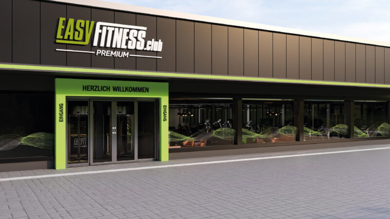 Modernes Äußeres eines EASYFITNESS.club Fitnessstudio-Franchise mit großen Glasfenstern, grüner Beschilderung und einem einladenden Eingang mit der Aufschrift HERZLICH WILLKOMMEN und EINGANG über Doppeltüren.